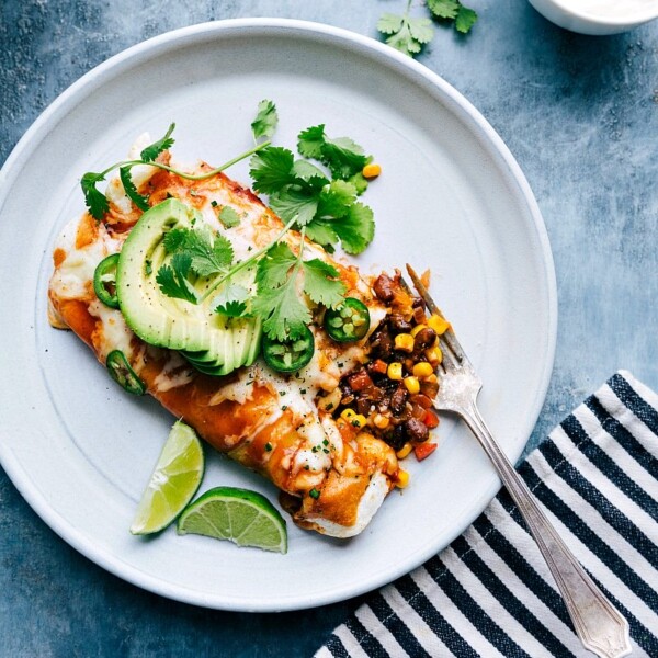 Easy vegetarian enchiladas on a plate with one cut open to reveal the tasty ingredients.