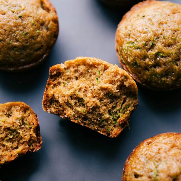 The finished healthy zucchini muffins, one split in half to reveal the moist interior.