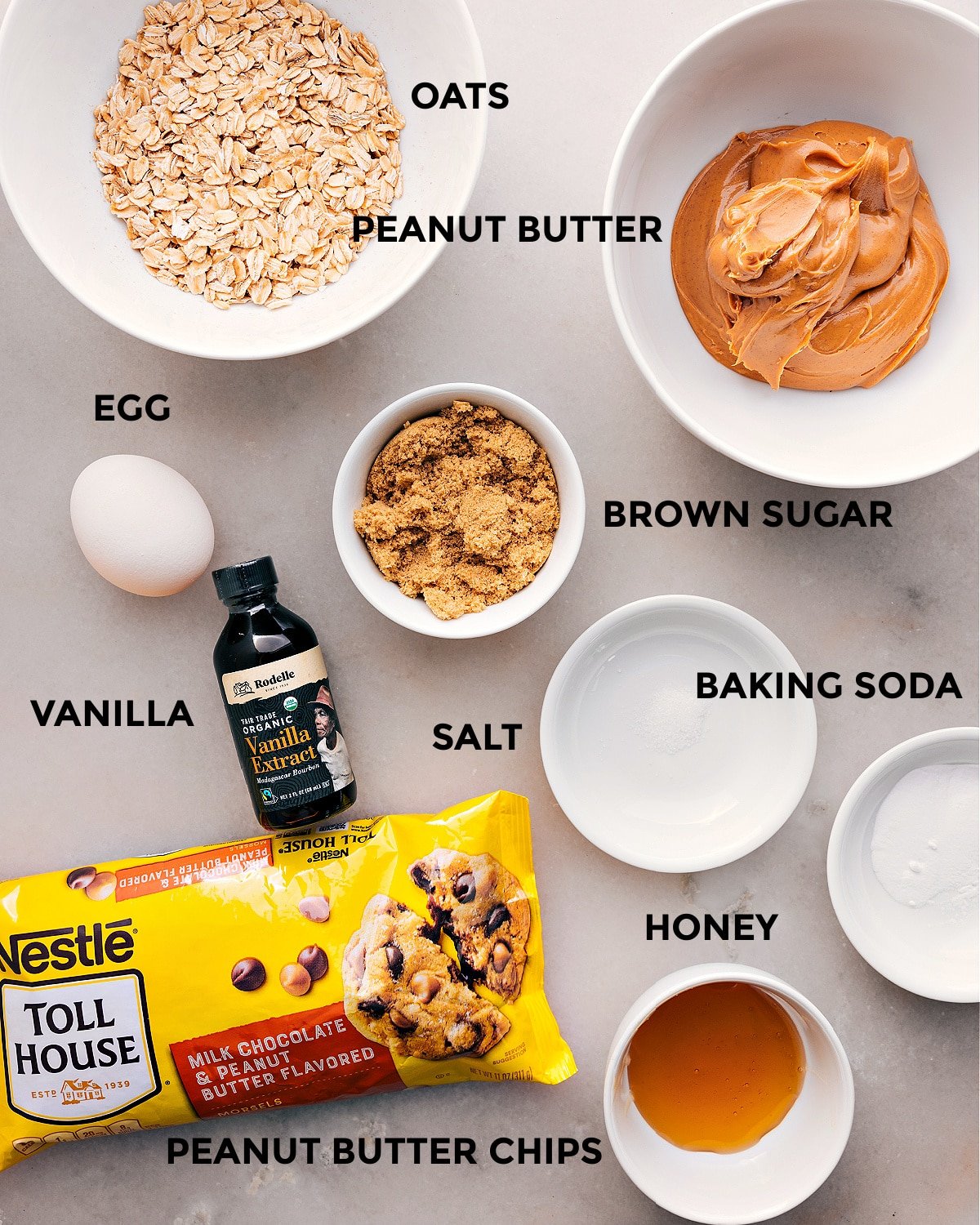 All the ingredients prepped for easy assembly, including oats, peanut butter, sugar, baking soda, salt, vanilla, honey, and peanut butter chips.