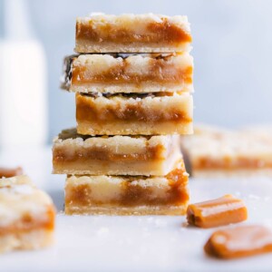 A stack of freshly baked caramel cookie bars, sliced to display a soft and gooey caramel-filled interior, surrounded by a crisp golden crust, rich in flavor.