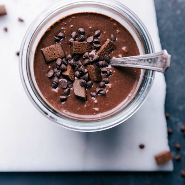 Brownie batter overnight oats, topped with chocolate chips and brownie bites for a sweet and delicious breakfast treat.