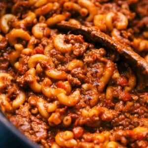 Freshly cooked goulash in a skillet with a wooden spoon, ready for serving.