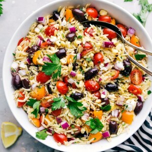 Delicious and healthy orzo pasta salad in a bowl with spoons, ready to be served.