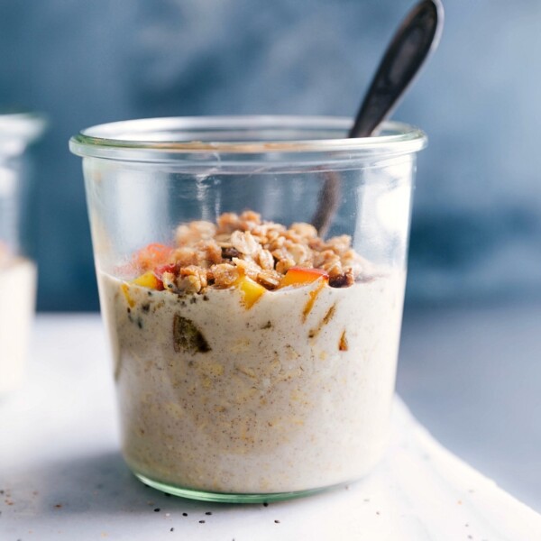 Peach overnight oats in a bowl, ready to be eaten, topped with fresh peach slices and crunchy granola.