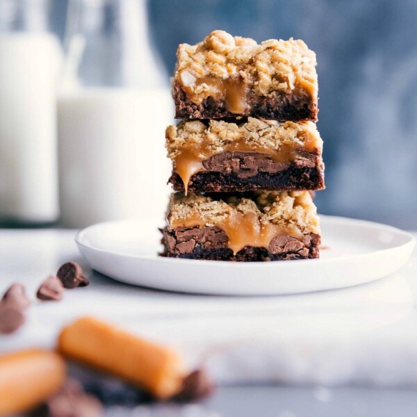 Brownie cookie bars stacked, with caramel oozing out from the center layers.