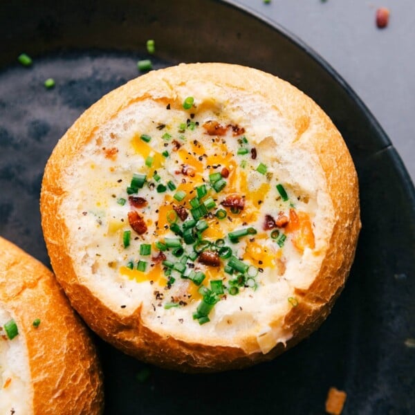 Hearty and warm potato soup served in a gorgeous bread bowl, topped with fresh herbs and cheese.