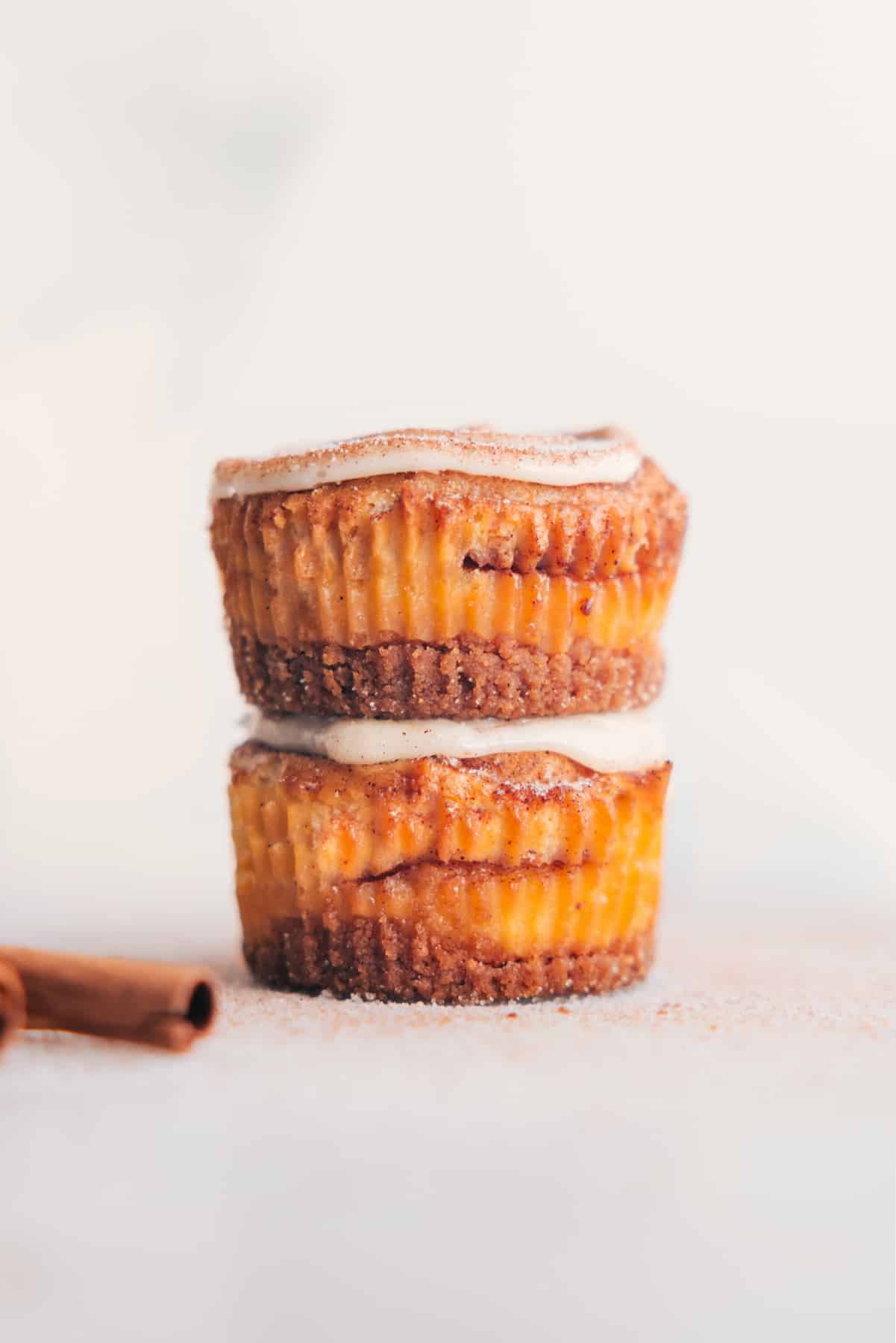 Cinnamon Roll Cheesecakes stacked together, topped with frosting.