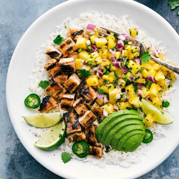 Ready-to-eat Pineapple Chicken over rice, with avocado and lime on the side.