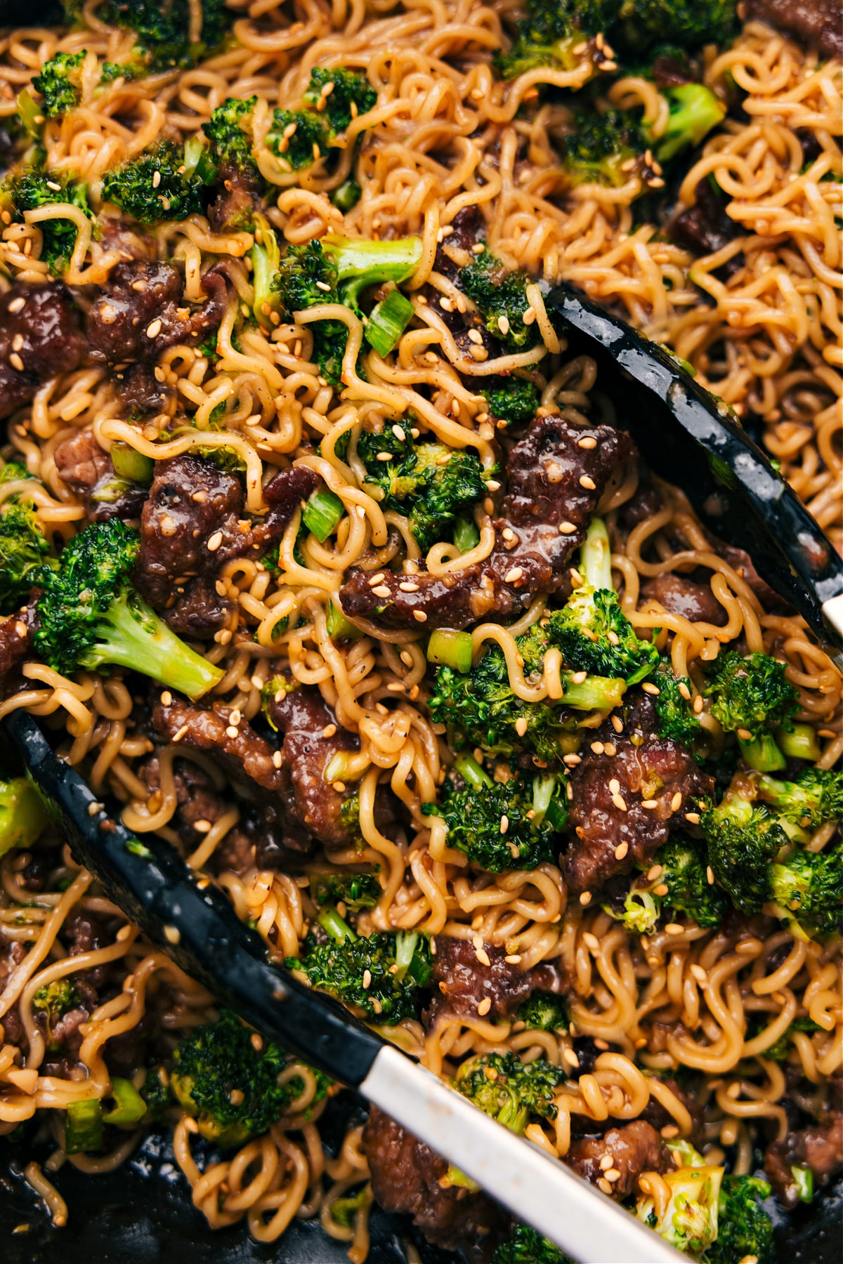 Beef and broccoli ramen in the pot with sesame seeds and green onions as garnish.