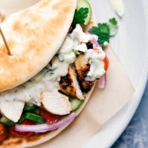 A complete chicken gyro, overflowing with chicken, vegetables, and sauce, wrapped in a soft pita, ready to be enjoyed as part of a chicken gyro recipe.