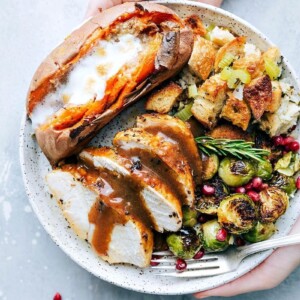 Plate abundantly filled with Thanksgiving staples, including turkey, cranberry sauce, stuffing, and vegetables.