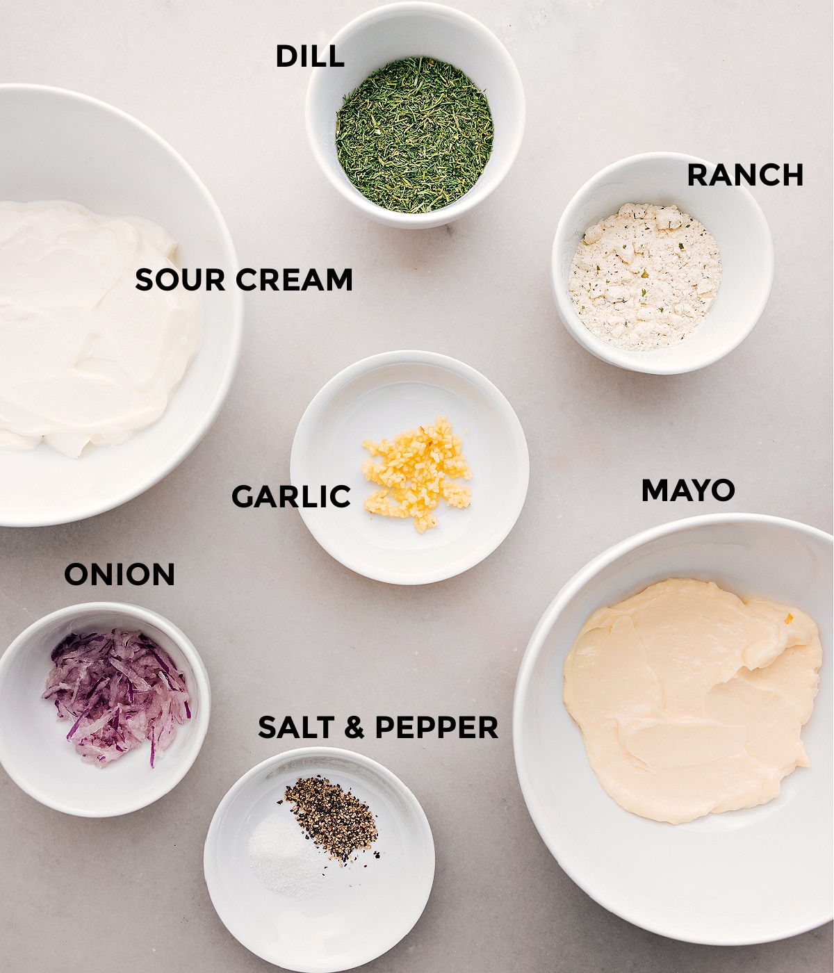 All the ingredients for this recipe—dill, ranch seasoning, sour cream, mayo, garlic, onion, salt, and pepper—are prepped and ready for easy assembly.