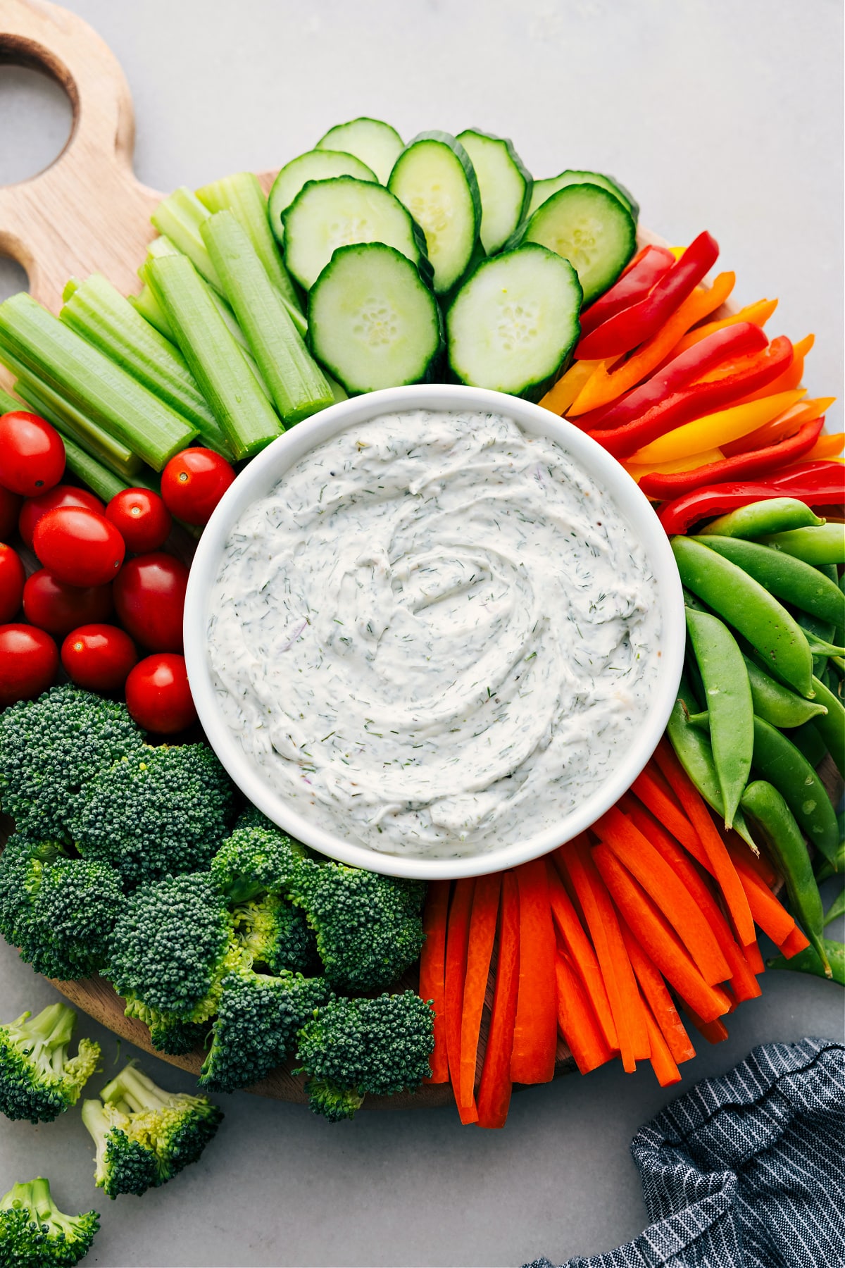 A platter of veggies surrounds a bowl of veggie dip in the center, all set for hosting or snacking.