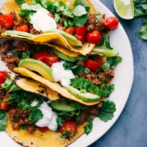 Tantalizing turkey tacos on a plate, adorned with toppings and accompanied by fresh lime wedges, eagerly awaiting to be savored.