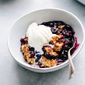 The finished, freshly baked dessert in a bowl, featuring a golden crumble topping and juicy filling, topped with a scoop of creamy vanilla ice cream, ready to be enjoyed.