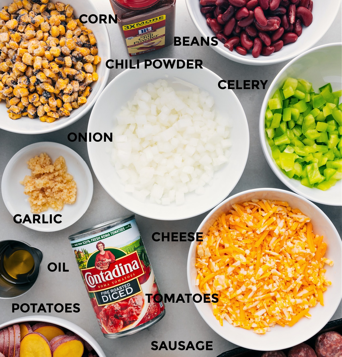 All the ingredients in this recipe are prepped for easy assembly, including the veggies, cheese, tomatoes, potatoes, oil, corn, beans, and seasonings.