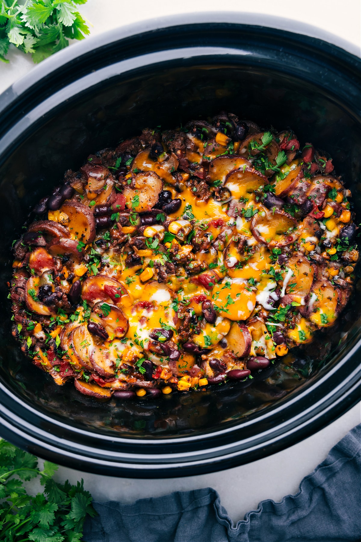 Crockpot Cowboy Casserole with freshly grated and melted cheese on top, still in the crockpot.