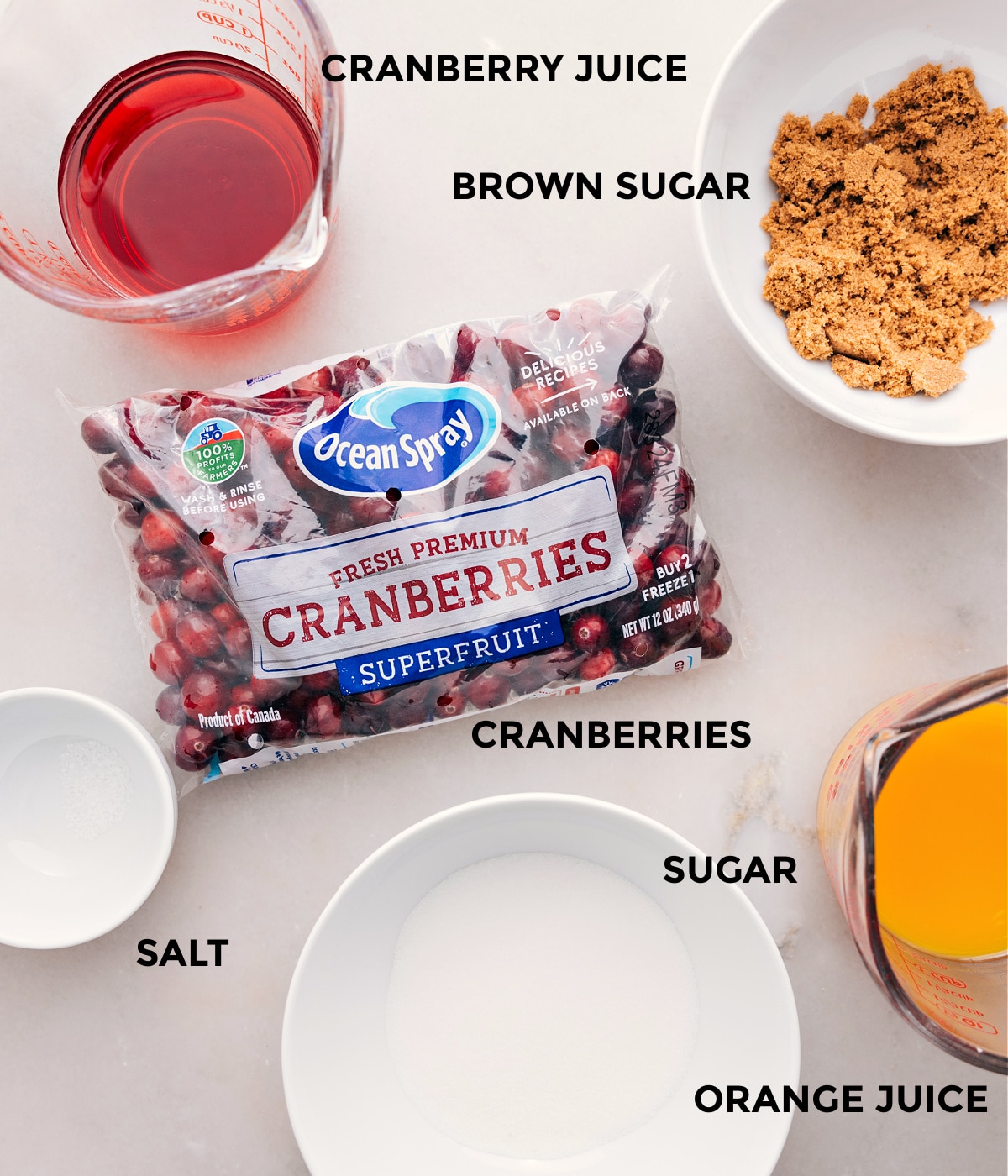 This recipe's ingredients are prepped for easy assembly: cranberries, sugar, orange juice, brown sugar, cranberry juice, and salt.