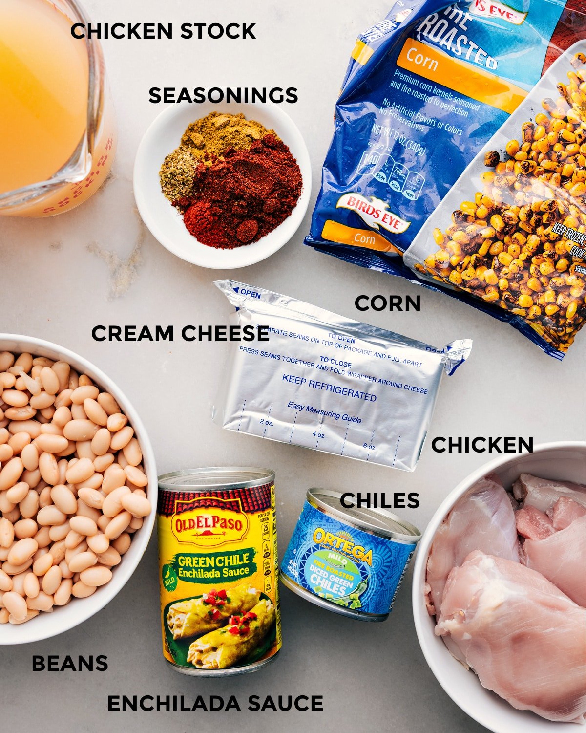 Prep all the ingredients for this recipe, including stock, seasonings, corn, cream cheese, meat, chiles, beans, and enchilada sauce, for easy assembly.