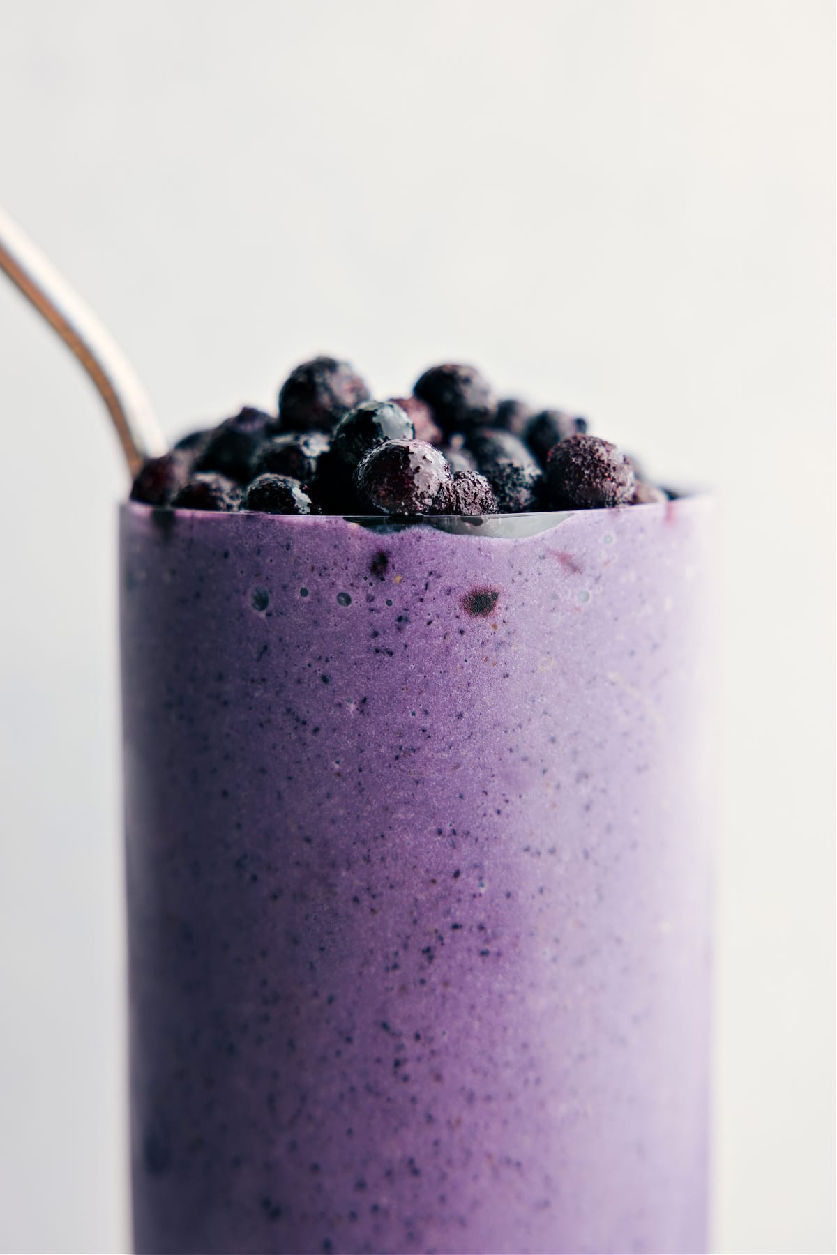 Blueberry smoothie freshly blended with frozen blueberries on top ready to be enjoyed.