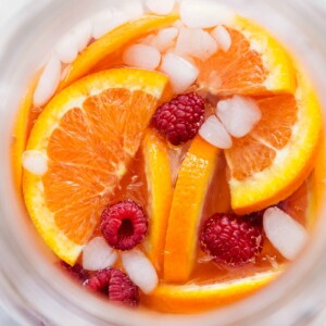 Drink with the oranges, raspberries, and ice on top, ready to be enjoyed.