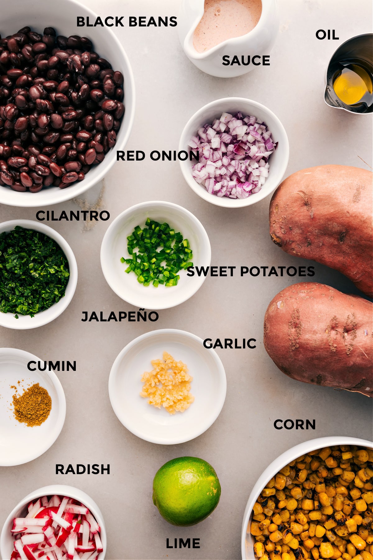 This recipe organizes all the ingredients for easy assembly: black beans, sauce, oil, onion, cilantro, sweet potatoes, corn, garlic, radishes, and lime.