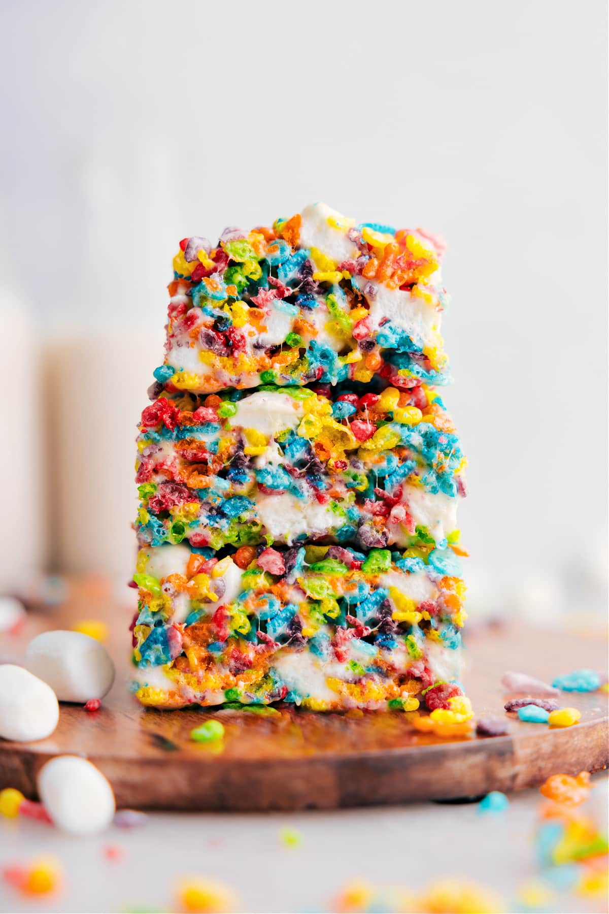 Fruity Pebbles Rice Krispies Treats stacked on top of each other showing the gooey desserts.