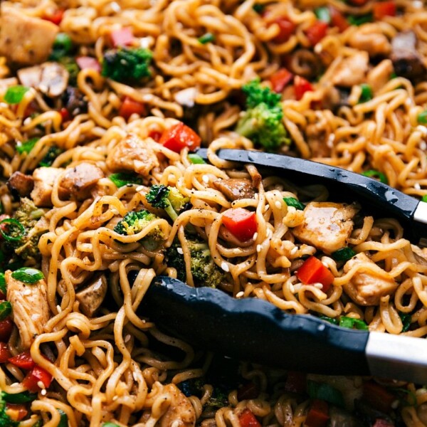 Fnished Chicken Ramen in a skillet with tongs holding some of the noodles.