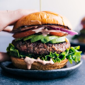 Gorgeous finished black bean burger with fresh vegetables sandwiched between a beautiful buttered bun.