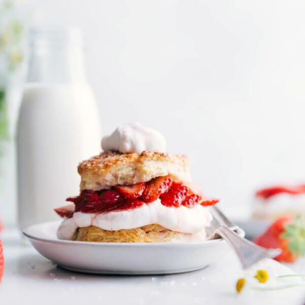 Strawberry Shortcake served with a generous dollop of whipped cream on top, accompanied by a fork on the side of the plate, ready to be enjoyed.