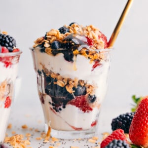 Layered yogurt parfait in a cup, showcasing layers of creamy yogurt, fresh fruit, drizzles of honey, and crunchy granola on top.