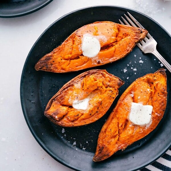 Baked sweet potatoes on a plate with melting butter on top, ready to be enjoyed.