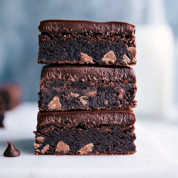 Three gluten-free brownies stacked on top of each other, displaying a fudgy, rich interior packed with gooey chocolate chips, ready to be enjoyed.