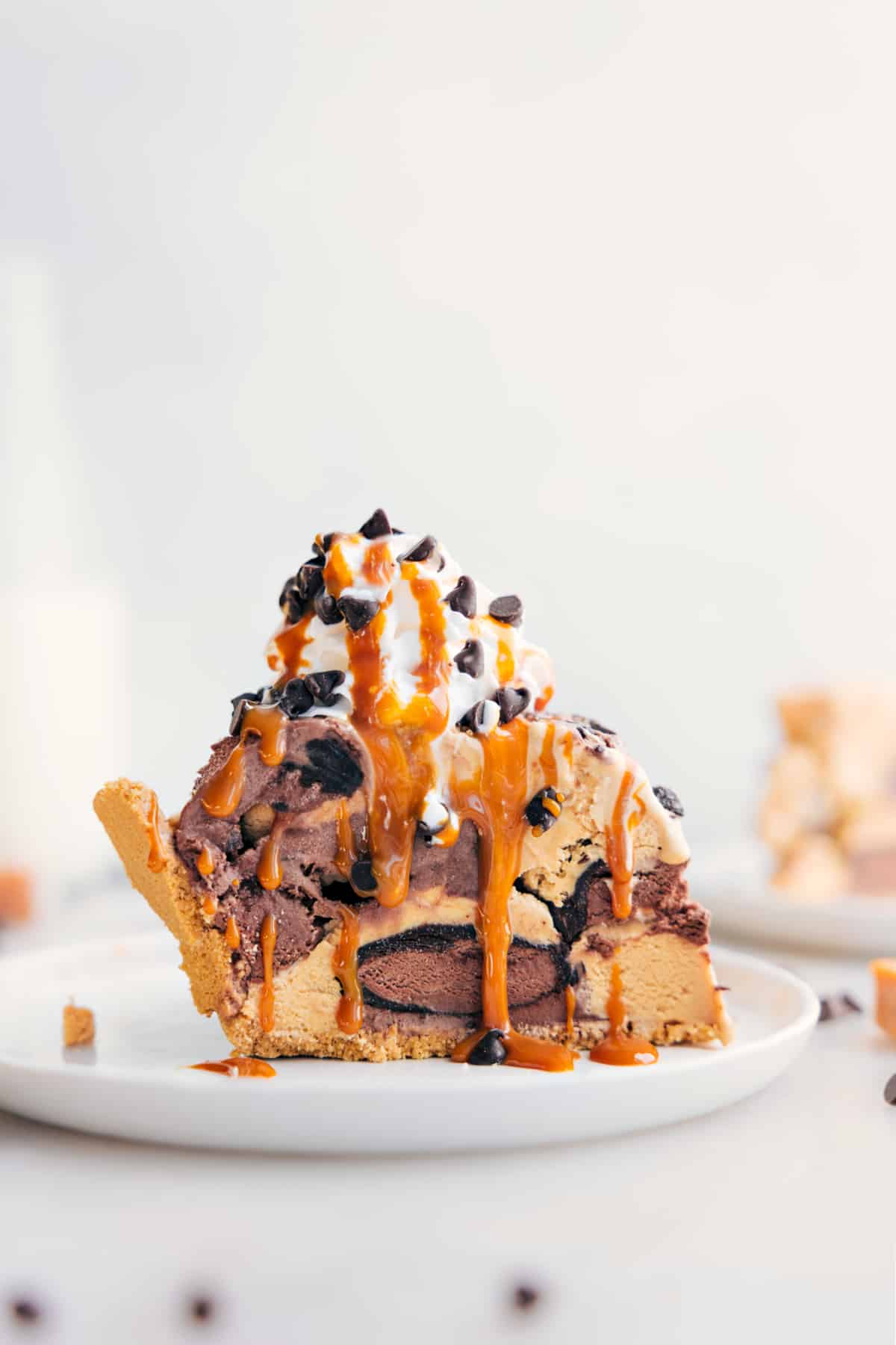 Slice of Ice Cream Pie with whipped cream, drizzle of caramel, and chocolate chips on top.