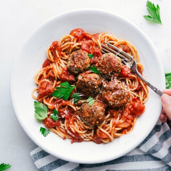 A bowl of finished turkey meatballs nestled over a bed of spaghetti, generously coated with marinara sauce and topped with fresh herbs, creating a hearty and inviting meal ready to be enjoyed.