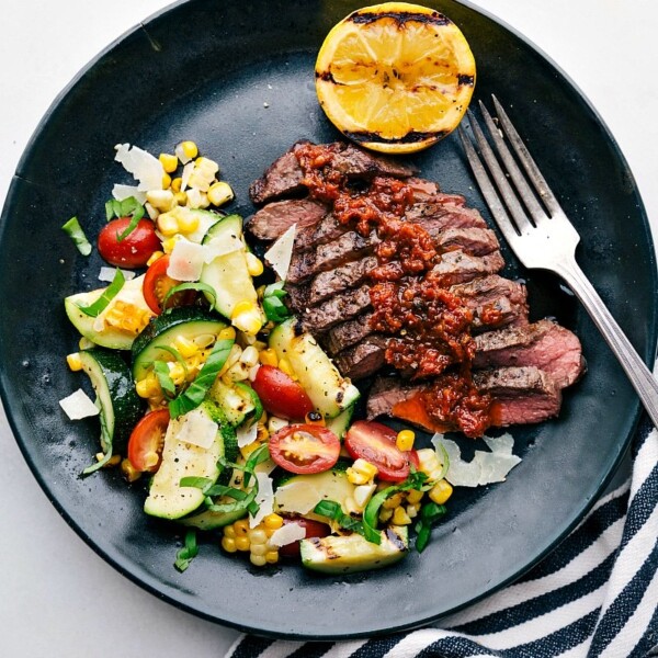 A succulent and tender grilled flat iron steak served with a refreshing zucchini and corn salad on the side, promising a delicious and satisfying meal.