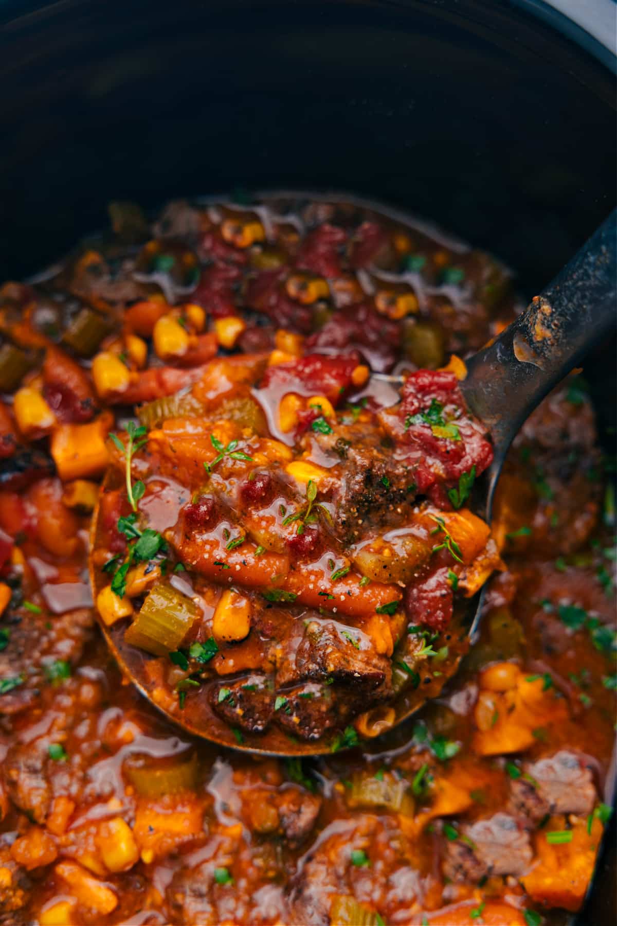 The sweet potato stew in the slow cooker, with a big ladle of stew being served.