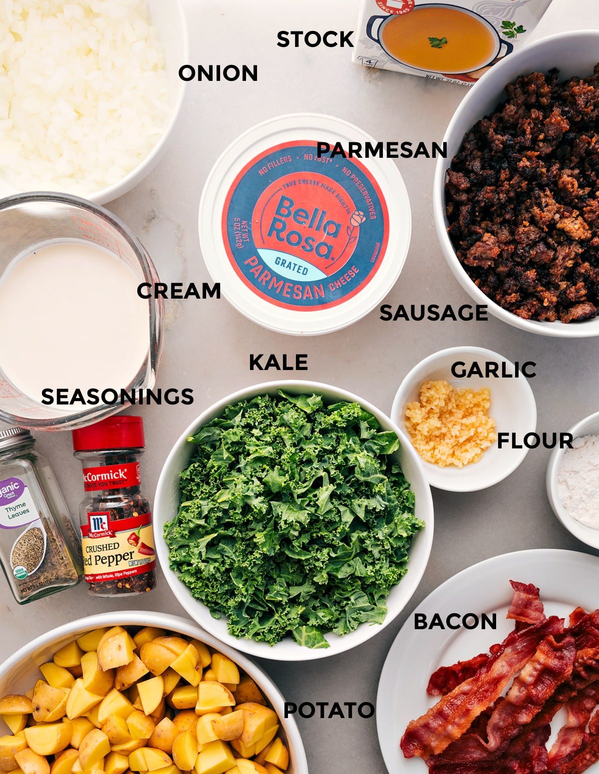 This recipe has all the ingredients prepped for easy assembly: stock, onion, Parmesan, sausage, cream, kale, garlic, flour, seasonings, bacon, and potatoes.