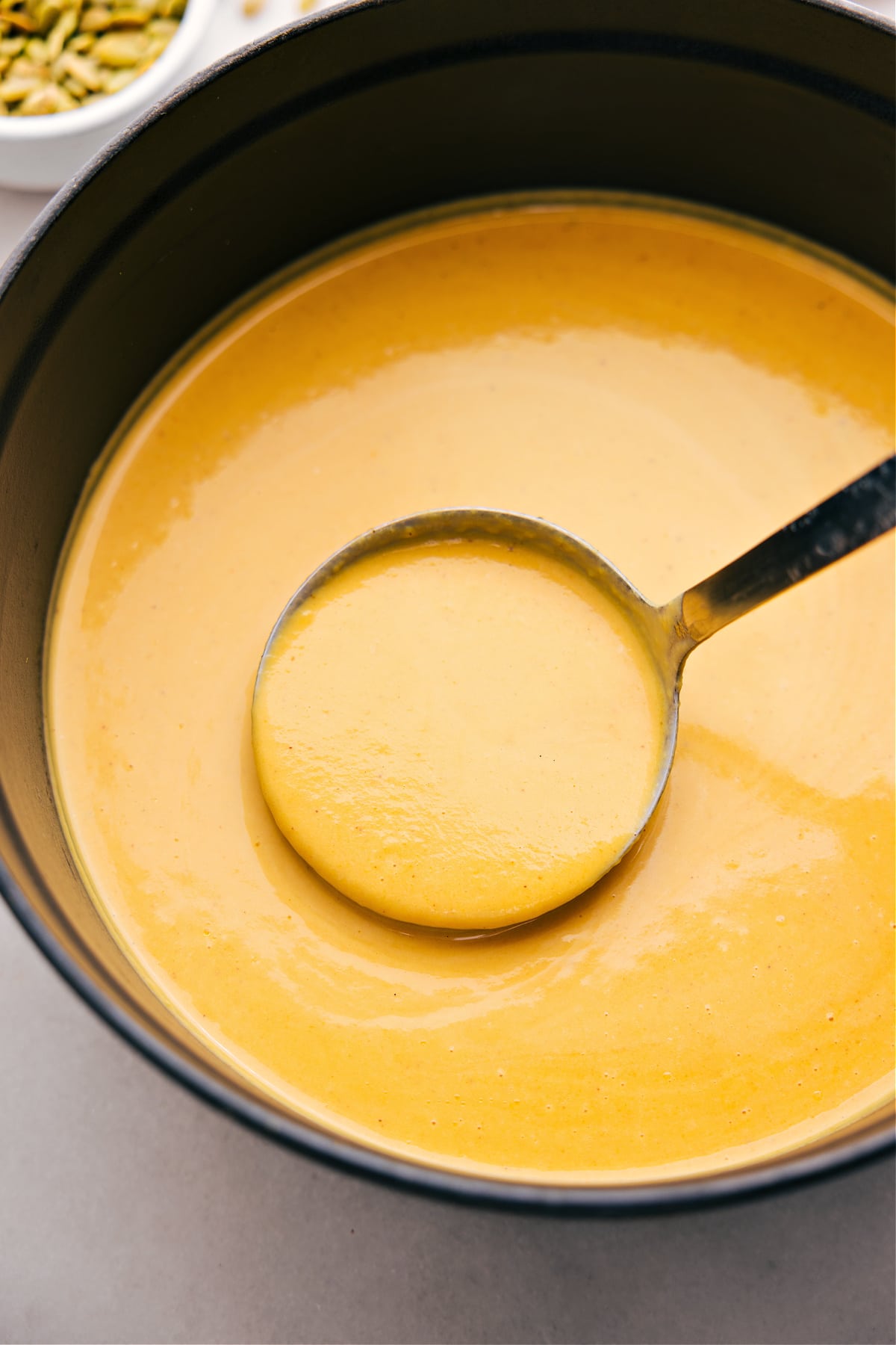 Butternut squash soup in the pot with a big ladle full coming out.