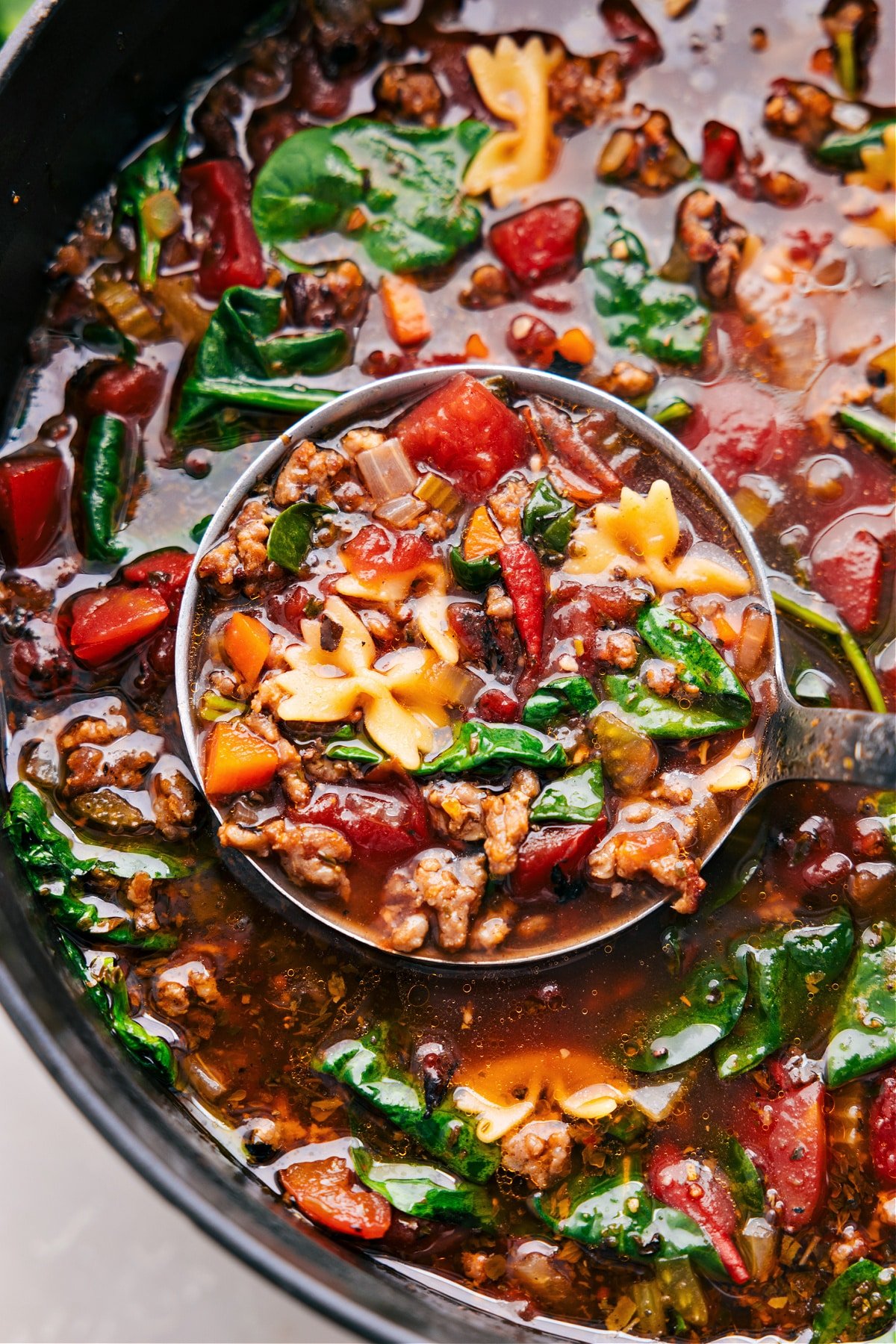 A big ladle scoops up a hearty serving of pasta soup.