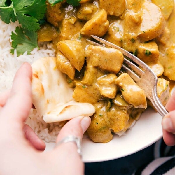 Yellow chicken curry served over rice and scooped onto naan bread.