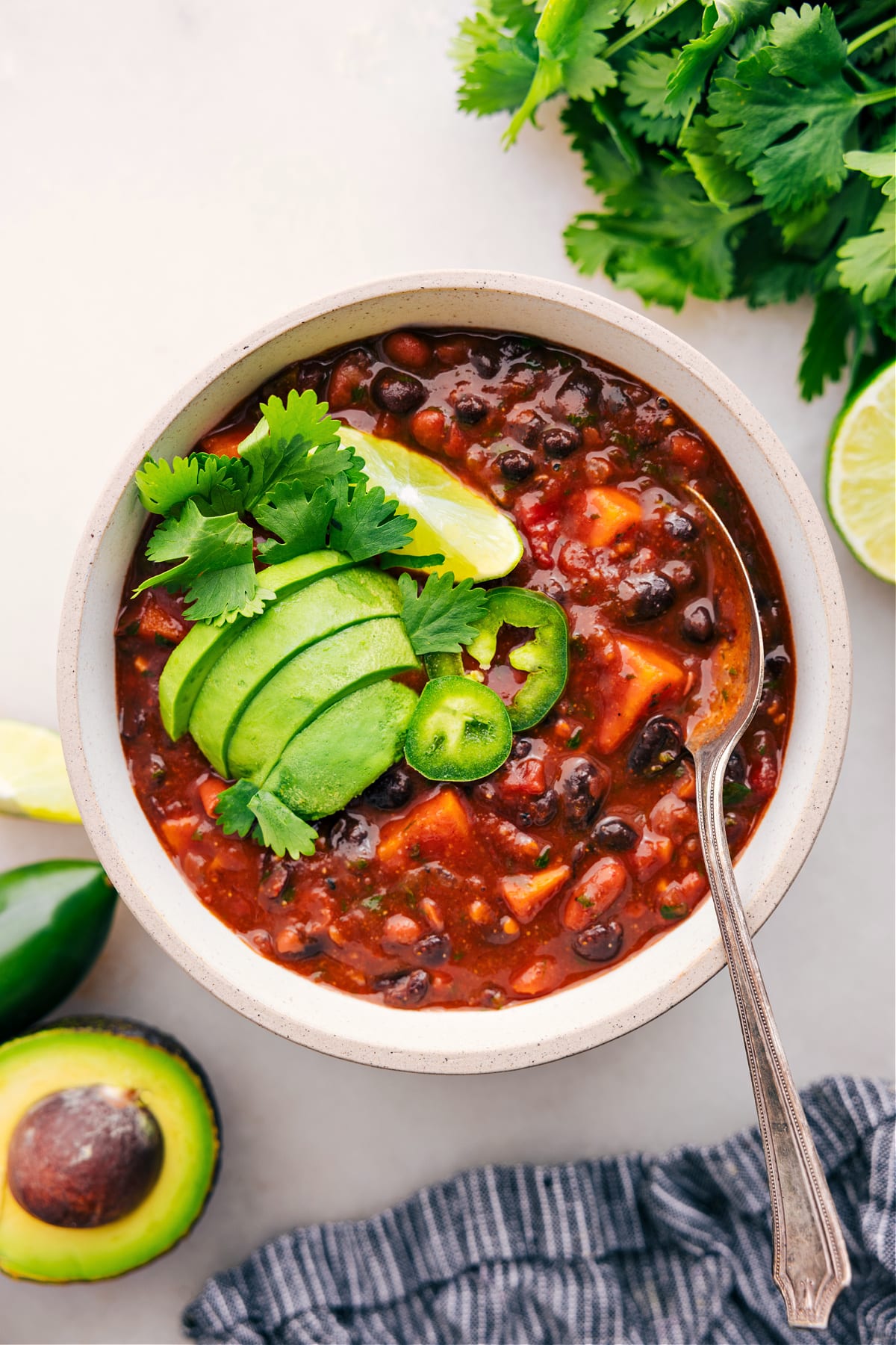 Sweet Potato Chili served in a bowl, topped with cilantro, jalapeño, lime, and avocado.