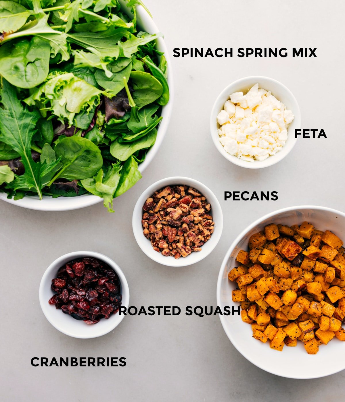 All the ingredients in this recipe, including the greens, feta, pecans, roasted squash, and cranberries, are prepped for easy assembly.