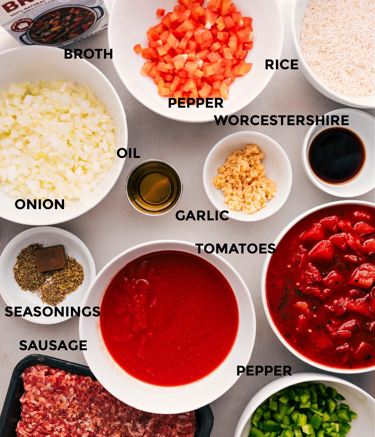 All the ingredients for this recipe are prepped and ready for easy assembly: peppers, onions, tomatoes, broth, meat, seasonings, garlic, Worcestershire, rice, and oil.