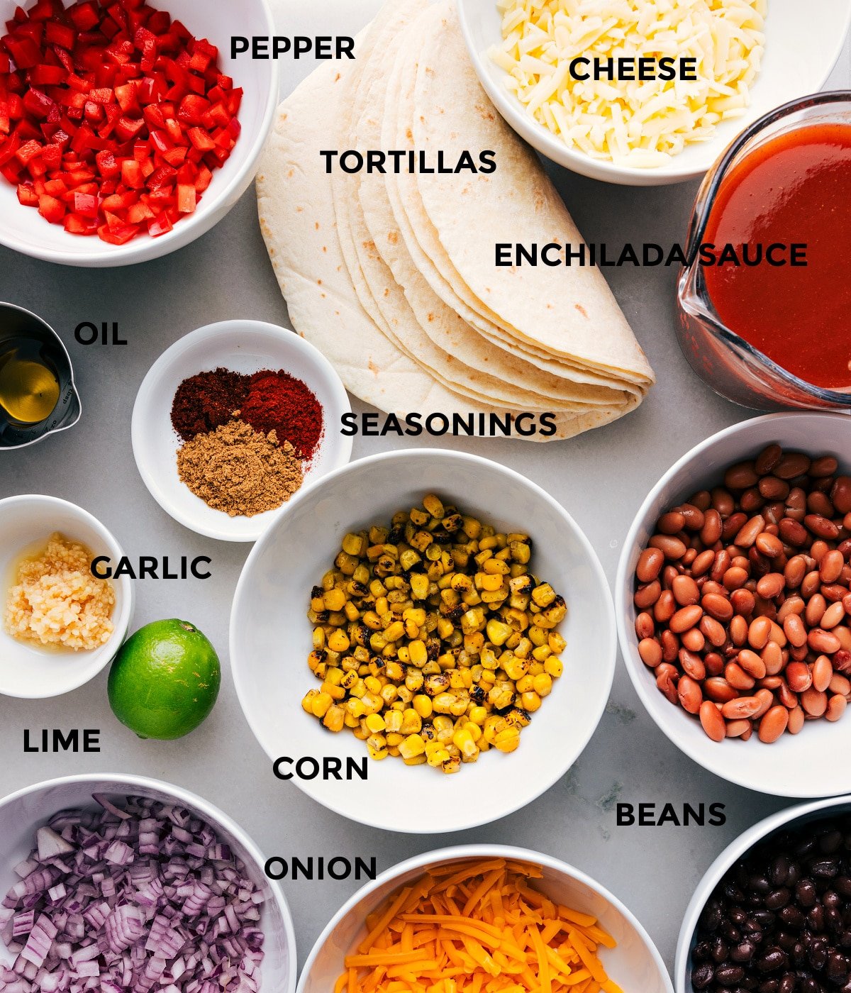 All the ingredients prepped for easy assembly, including veggies, tortillas, sauce, corn, cheese, seasonings, and beans.