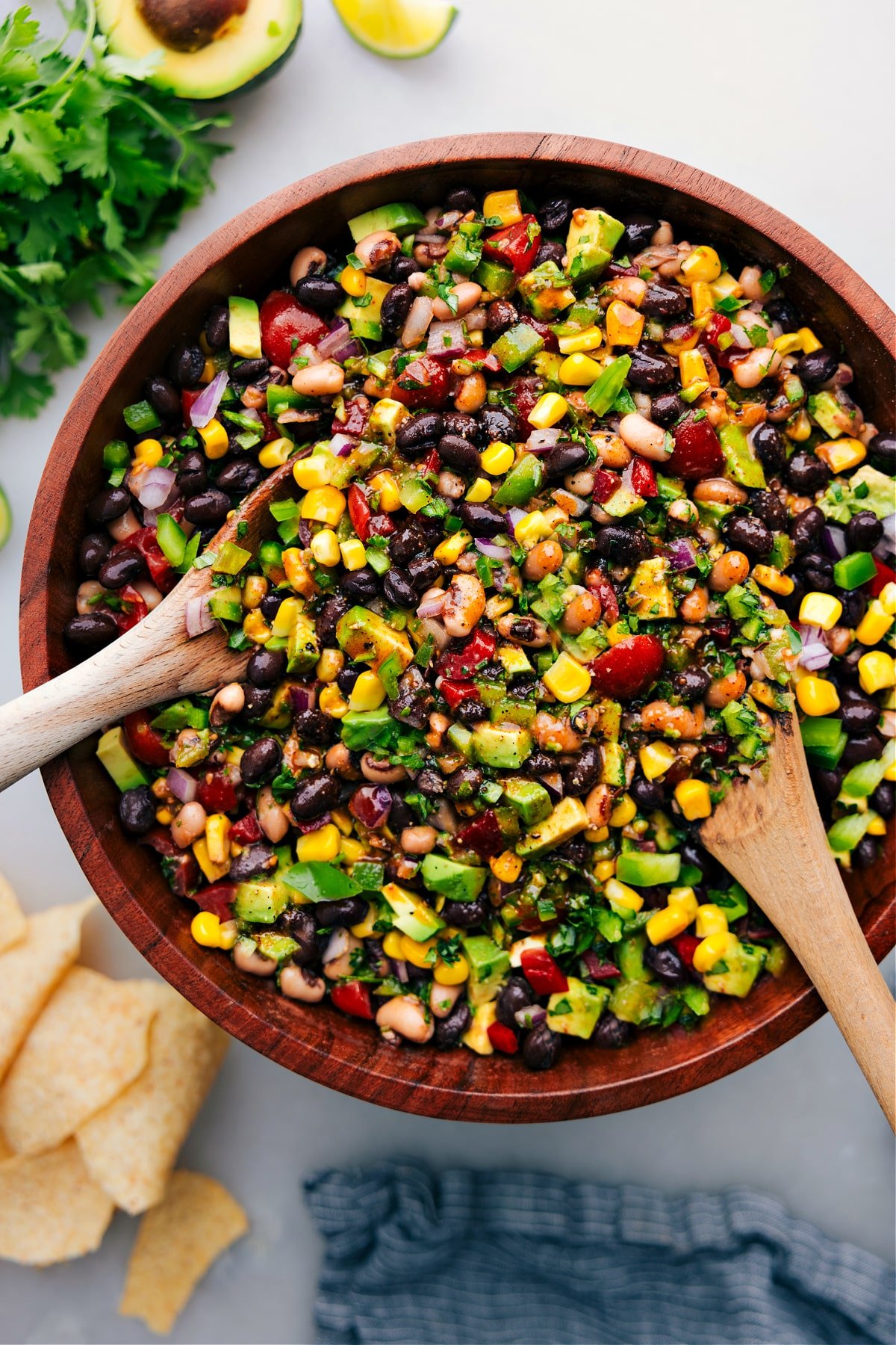 A big bowl of the cowboy caviar with two wooden spoons in it to be served up.