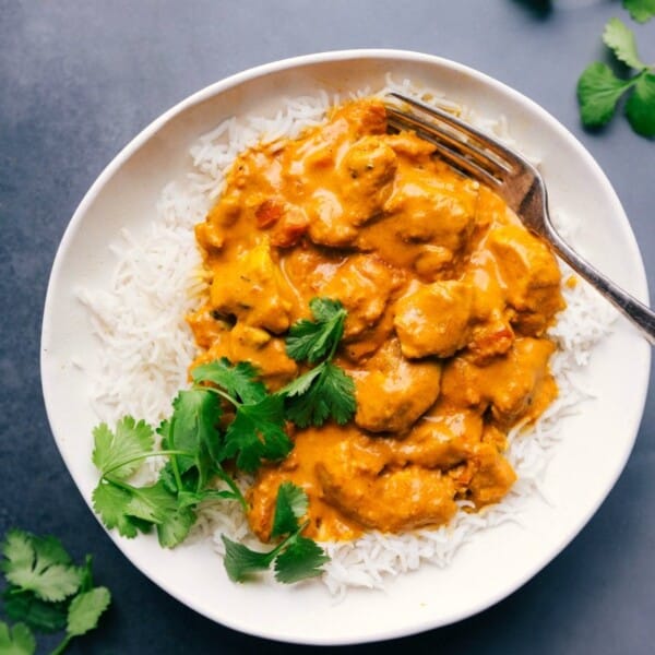 Plate of butter chicken served on rice, garnished with fresh cilantro.