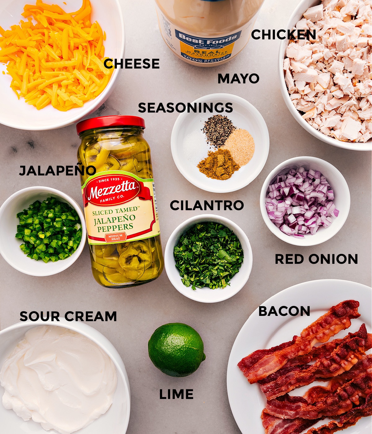 All the ingredients for this recipe are prepped for easy assembly, including cheese, mayo, eggs, seasonings, meat, and sour cream.