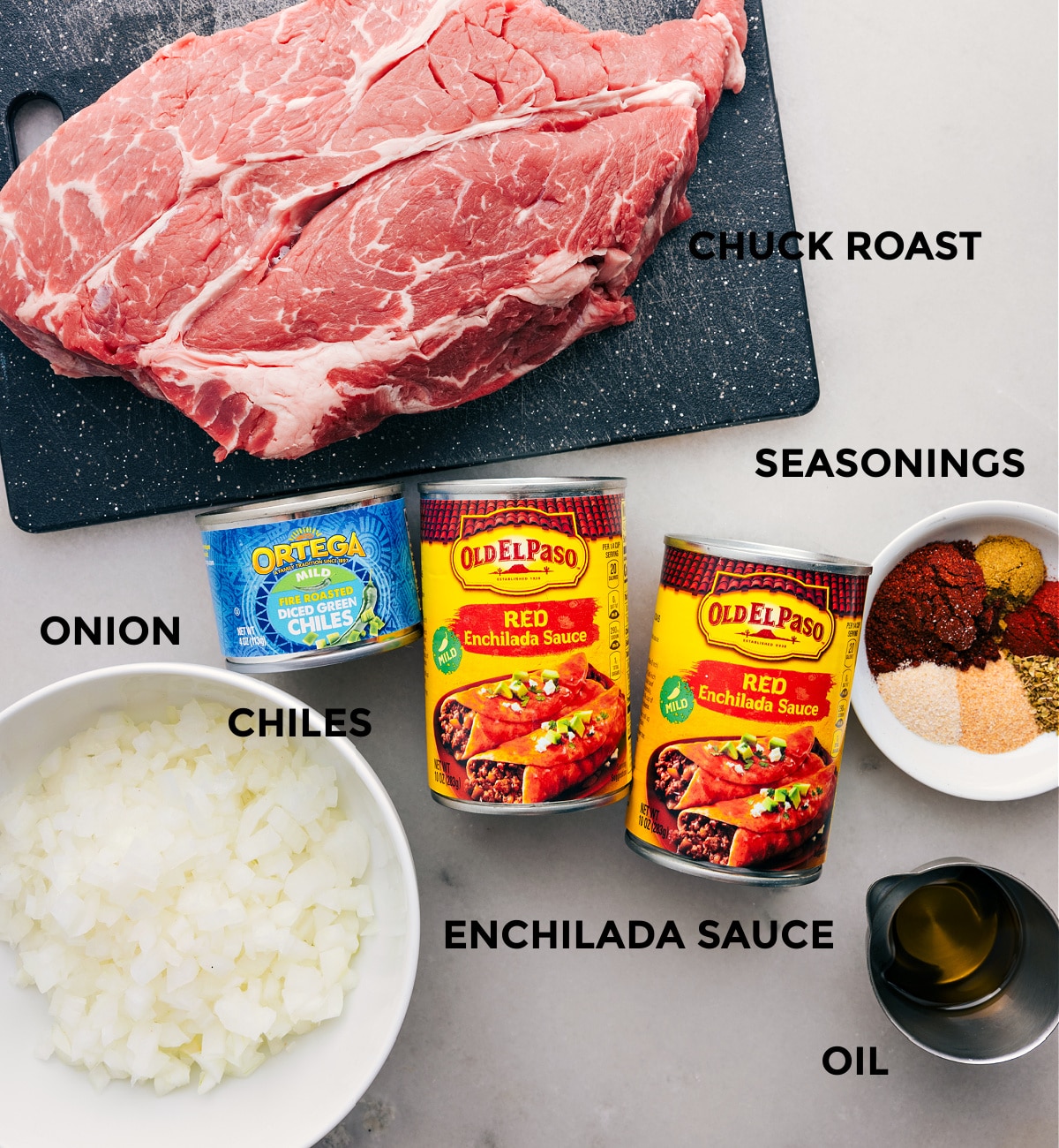 All the ingredients in this recipe prepped out for easy assembly including the meat, enchilada sauce, seasonings, onion, chiles, and oil.