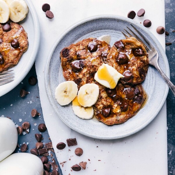 Gluten free banana pancakes with melted chocolate chips inside, topped with fresh banana slices, prepared for a delicious breakfast.